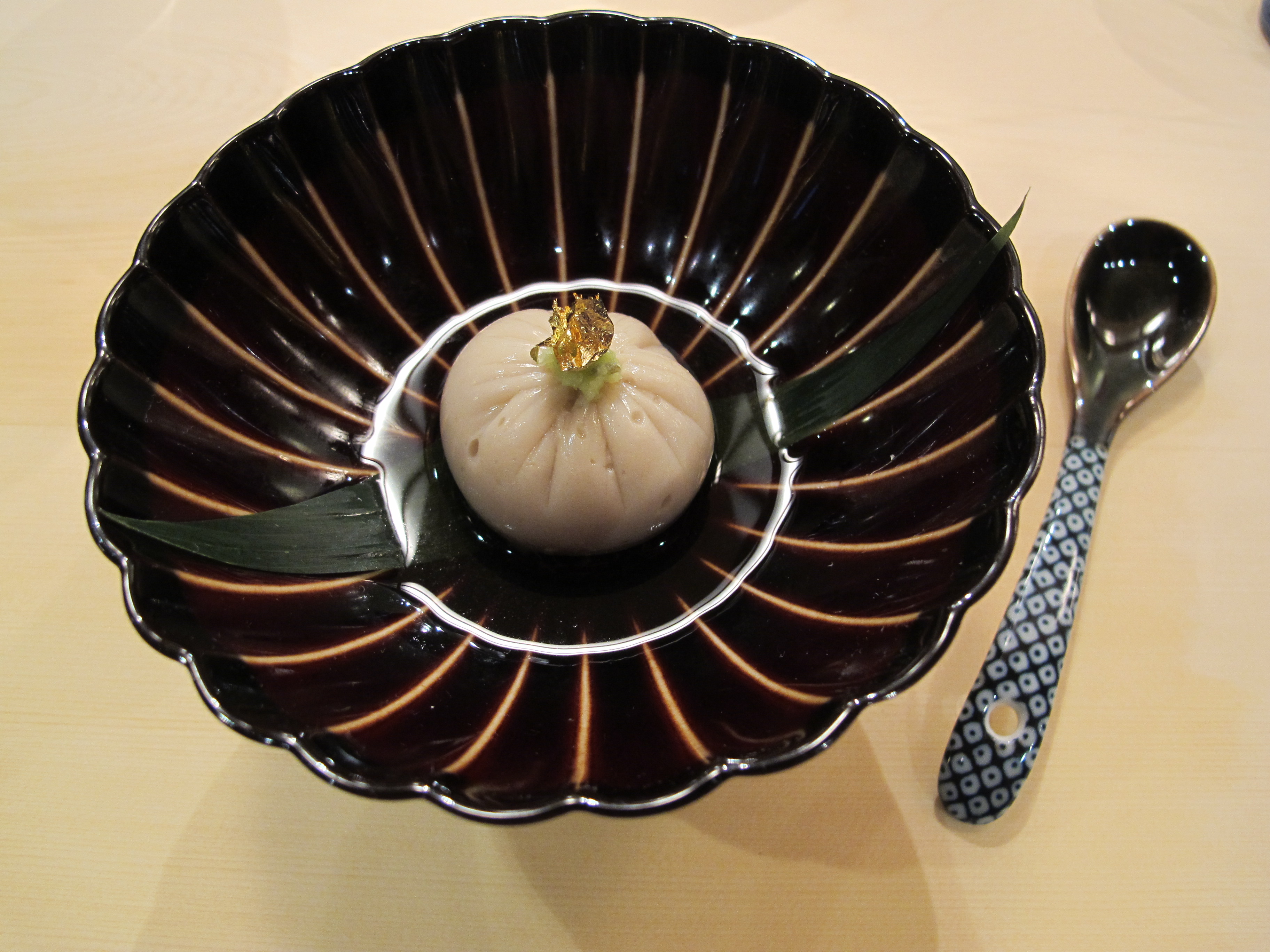 A tofu-sesame dumpling topped with a gold leaf